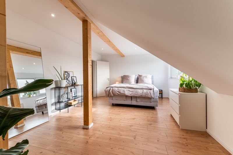 Schlafzimmer mit Doppelbett unter sichtbaren Holzbalken