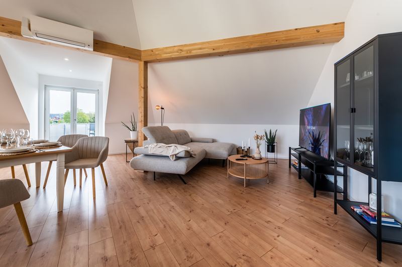 Wohnzimmer mit Sofa, Fernseher und angrenzendem Essbereich
