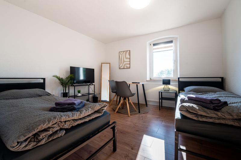 Schlafzimmer mit zwei Einzelbetten, Fernseher und Arbeitstisch