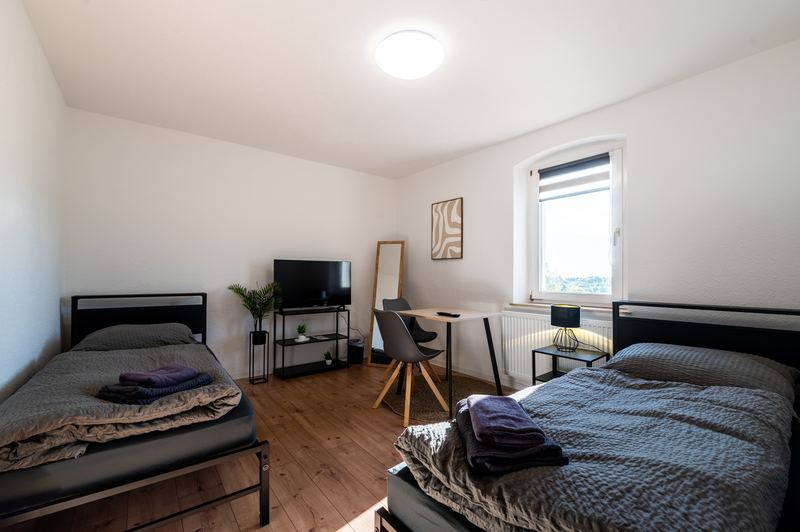 Schlafzimmer mit Einzelbetten und Arbeitsplatz für Monteure