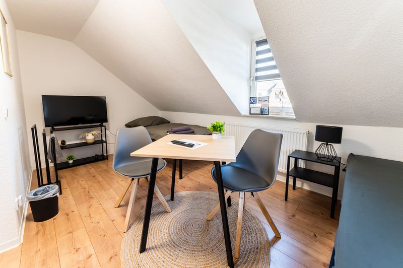 Heller Wohn- und Essbereich der Monteurwohnung in Dresden mit Esstisch und Fernseher